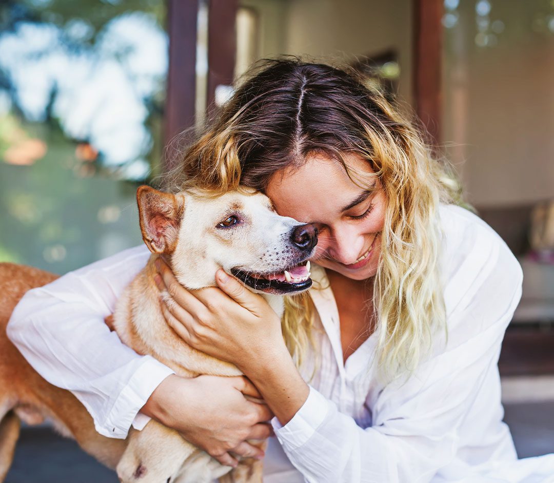 happy female hugging her dog outside on back patio